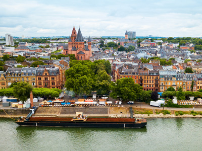 Luftaufnahme einer Stadt mit historischen Gebäuden, einem Fluss und einem Schiff im Vordergrund.
